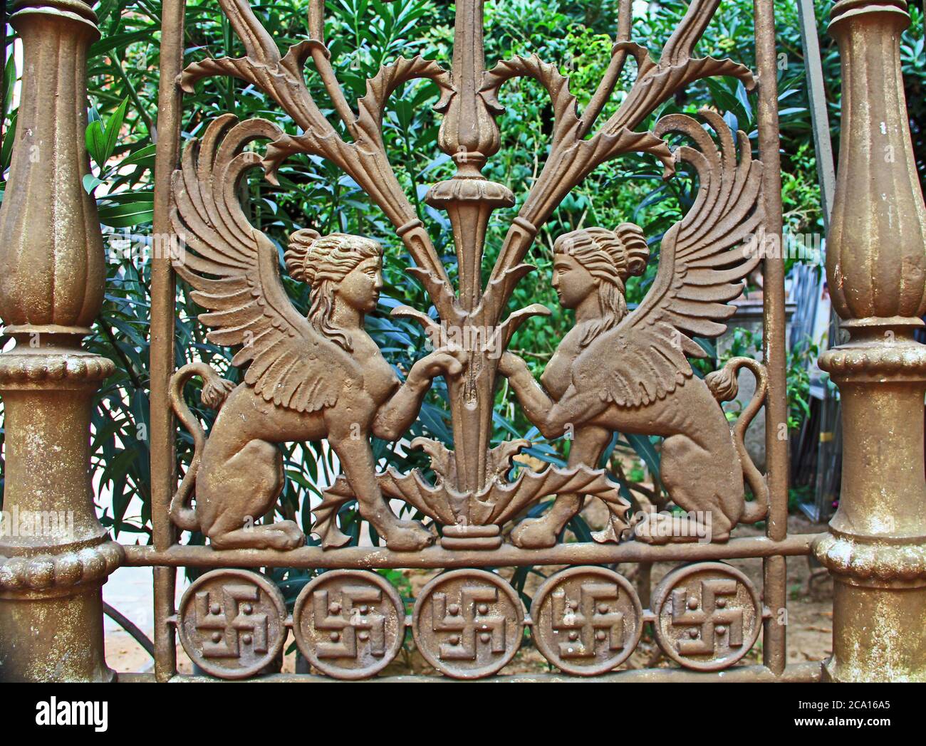 Dekorativer Metallzaun mit zwei mythischen Sphinxen, die sich gegenüberstehen, und religiöser Hakenkreuzgrenze in Athen, Griechenland. Stockfoto