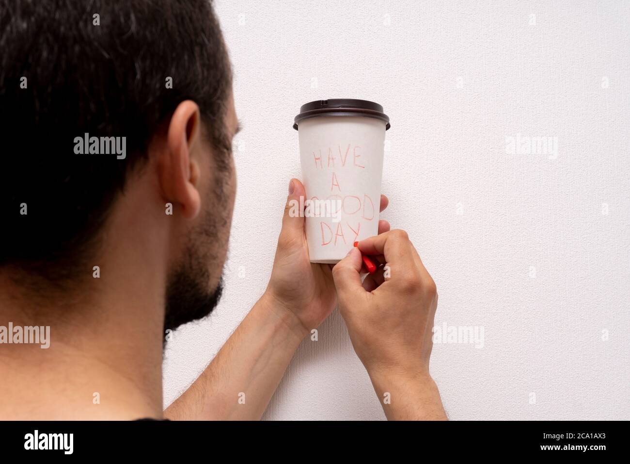 Kaukasischen Mann hält weiße Takeaway Papier Kaffeetasse und schreibt haben einen guten Tag Phrase Stockfoto