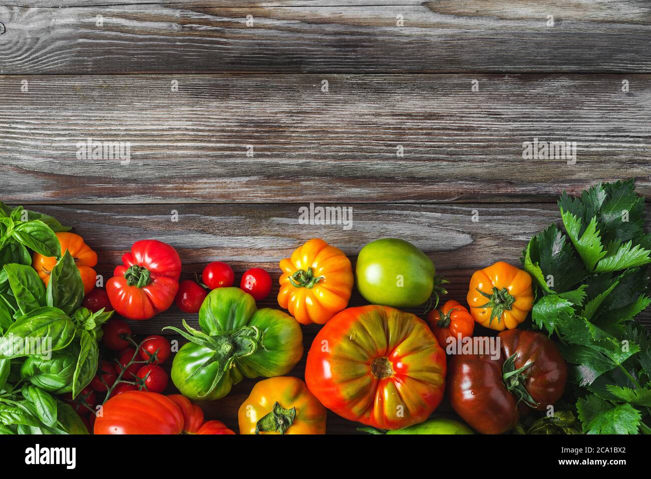 Frische bunte Bio-Gemüse Hintergrund. Rohe Tomaten und Kräuter auf rustikalem Holztisch. Gesunde Ernährung. Draufsicht mit Kopierraum Stockfoto