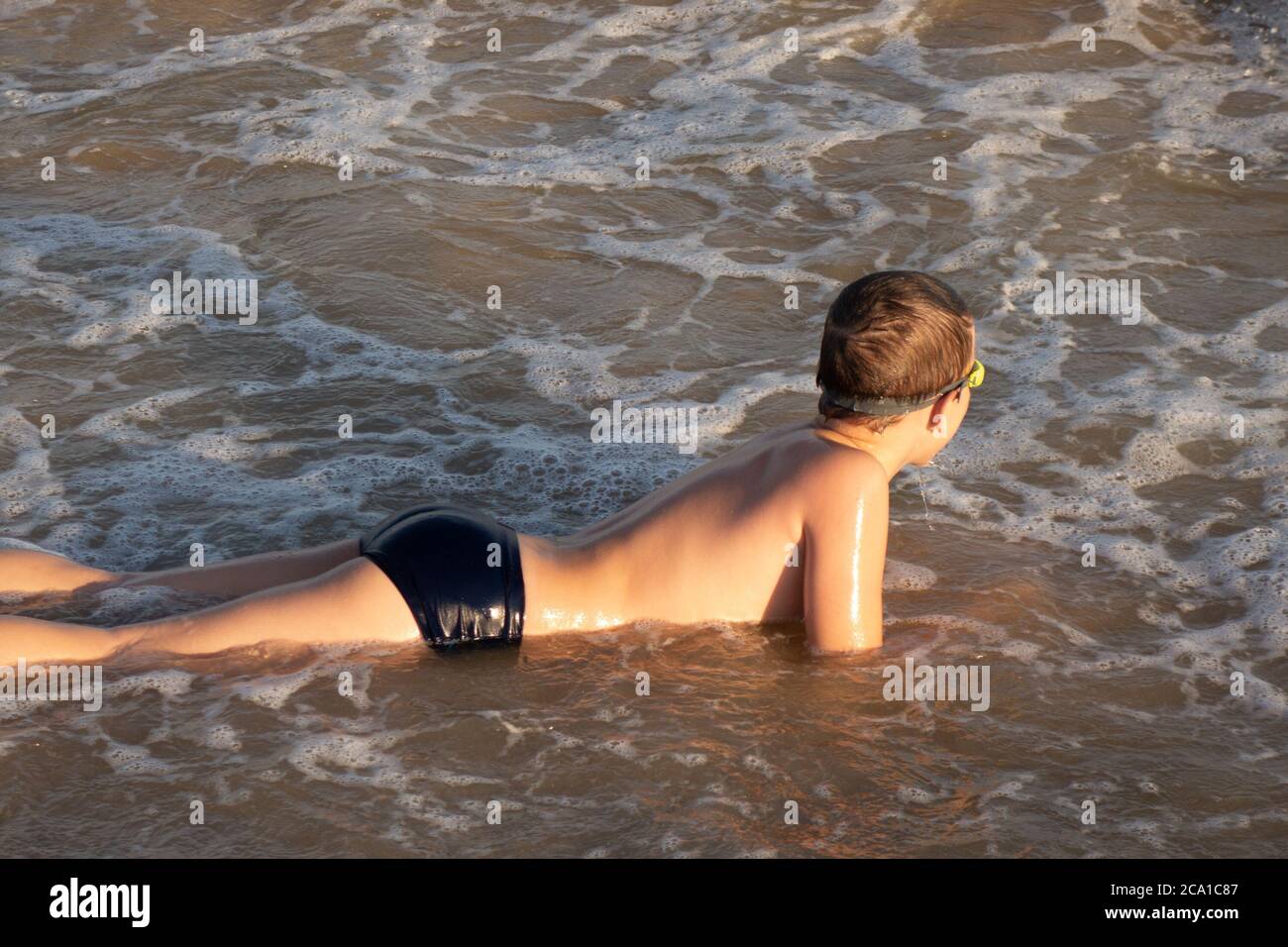 Junge 10 Jahre alt genießt Schwimmen in den Küstenwellen im Meer. Stockfoto
