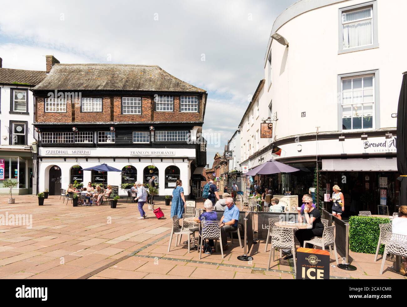 Menschen, die vor einem Café im Marktplatz von Carlisle City Centre sitzen, Cumbria, England, Großbritannien Stockfoto