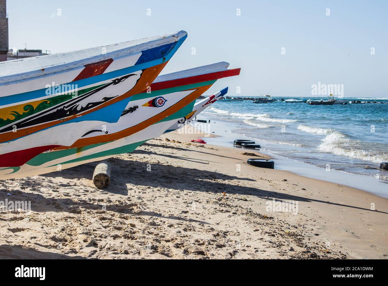 Typische Fischerboote in Yoff Dakar, Senegal, genannt Pirogue oder Piragua oder Piraga. Bunte Boote, die von Fischern am Strand in Afrika benutzt werden. Stockfoto