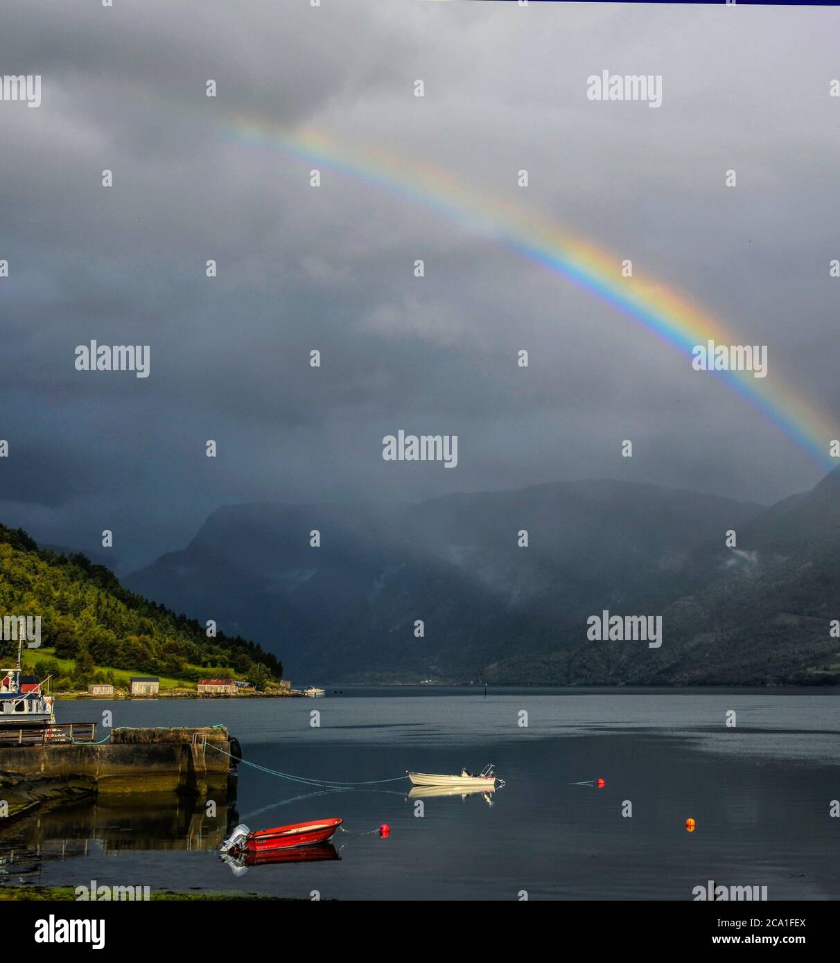 Ein Regenbogen über Booten in Solvorn, Norwegen. Solvorn liegt am östlichsten Punkt des Sognefjord Fjords in Norwegen. Stockfoto