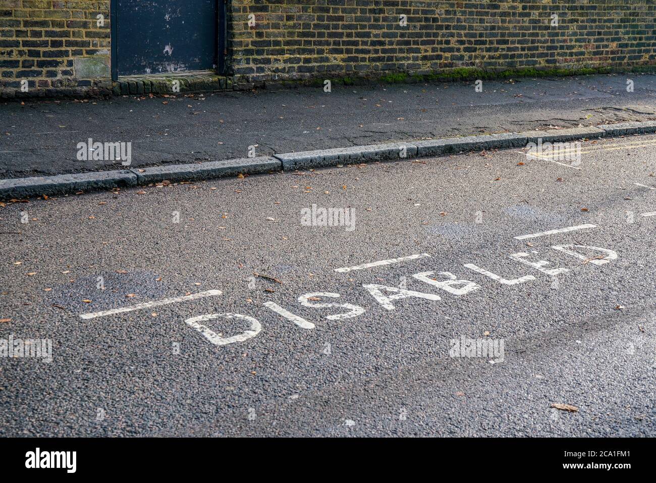 Wort BEHINDERTE geschrieben auf Asphalt in der Nähe reservierter Parkplatz an der Straße im äußeren London Stockfoto
