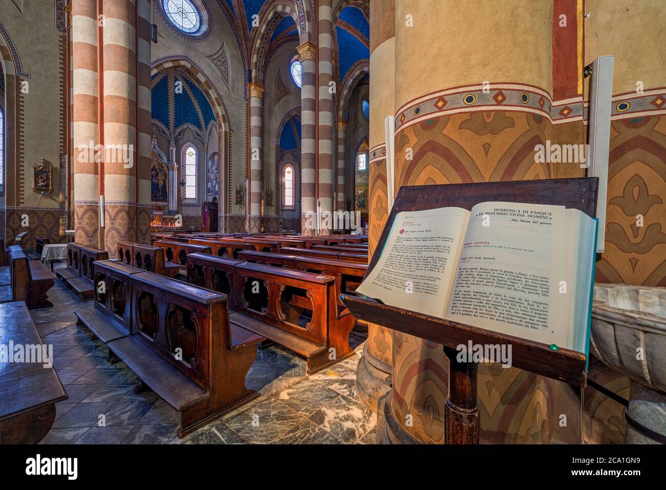 Heiliges Buch auf dem Stand als Holzbänke und Säulen im Hintergrund im Inneren von San Lorenzo - einer römisch-katholischen Kathedrale in Alba, Italien. Stockfoto