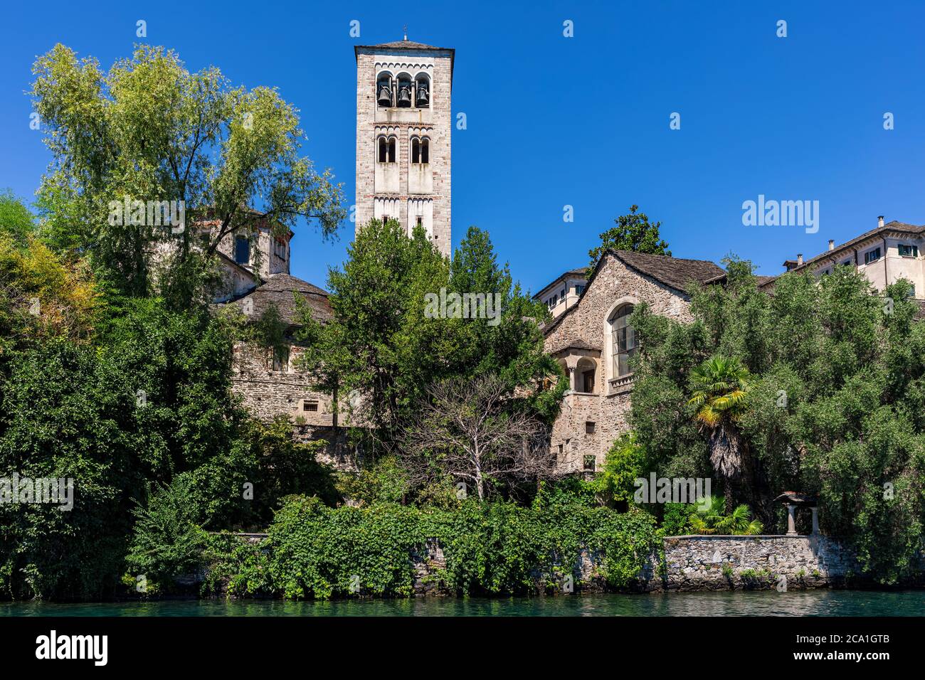 Mittelalterlicher Turm und altes Kloster unter grünen Bäumen unter blau schlaue auf der kleinen Insel San Giulio am See orta im Piemont, Norditalien. Stockfoto