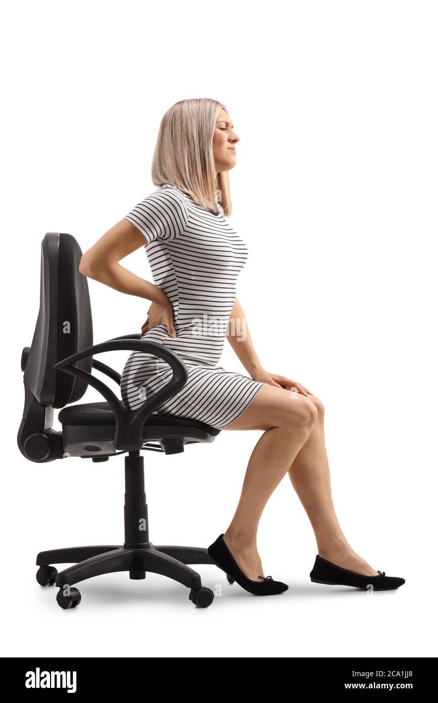 Junge Frau mit schmerzhaftem Rücken hält ihre Wirbelsäule und sitzt in einem Bürostuhl isoliert auf weißem Hintergrund Stockfoto