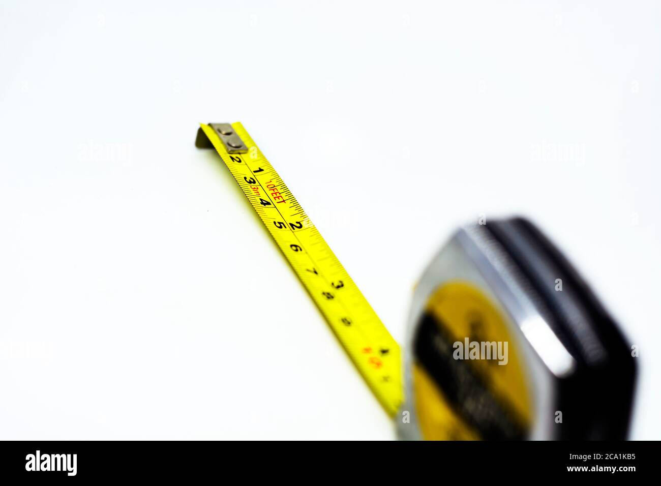Einziehbares gelbes Messband aus Metall, isoliert auf weißem Hintergrund. Messungen in Zentimetern und Füßen. Messgerät Stockfoto