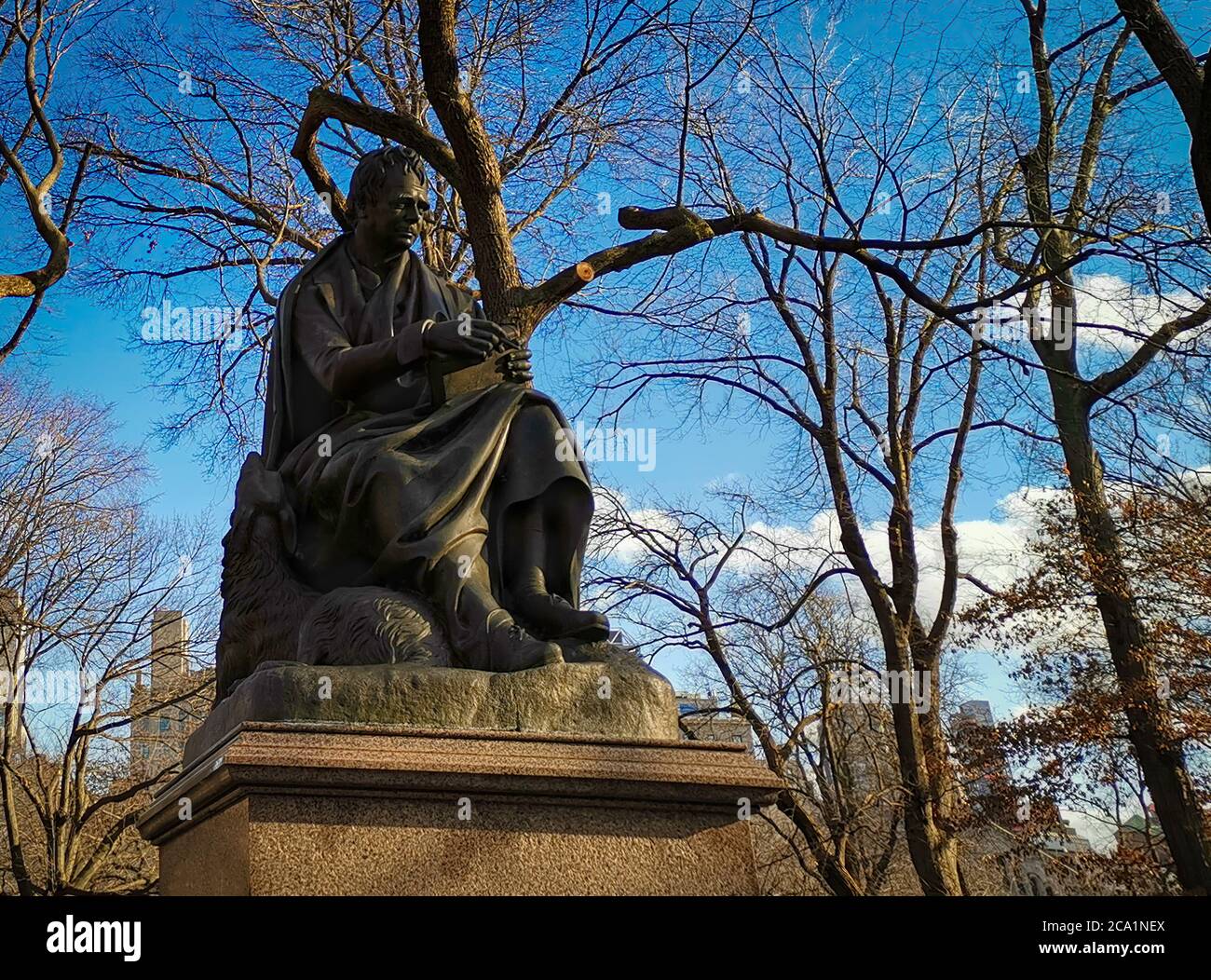 Statue von Walter Scott (von John Steell) im Central Park New York City Tageslicht Blick mit Bäumen, Wolkenkratzern und Wolken am Himmel Stockfoto