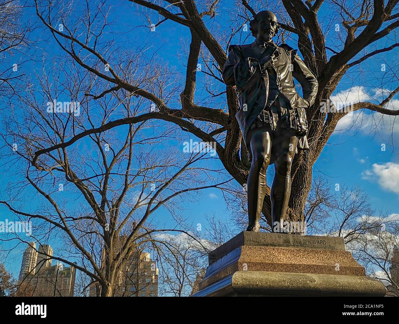 Statue von William Shakespeare (von John Quincy Adams ward) steht im Central Park New York City Tageslicht Blick mit Bäumen, Wolkenkratzern und Wolken Stockfoto