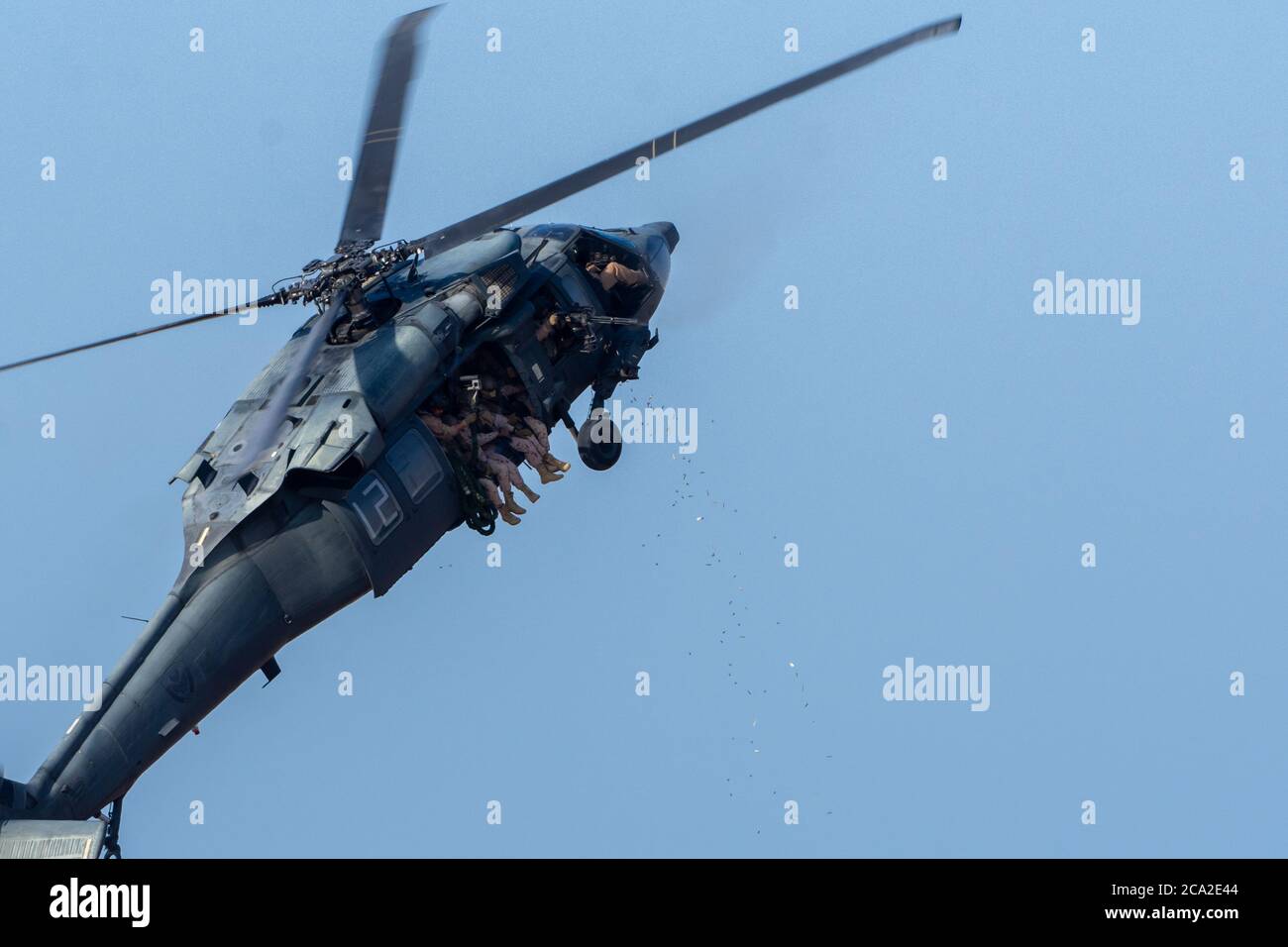 Militärkampf und Krieg mit Hubschrauber fliegen in das Chaos und Zerstörung. Soldaten hängen Schießmaschinengewehre mit Muschelfliegen an. Militärische Konz Stockfoto