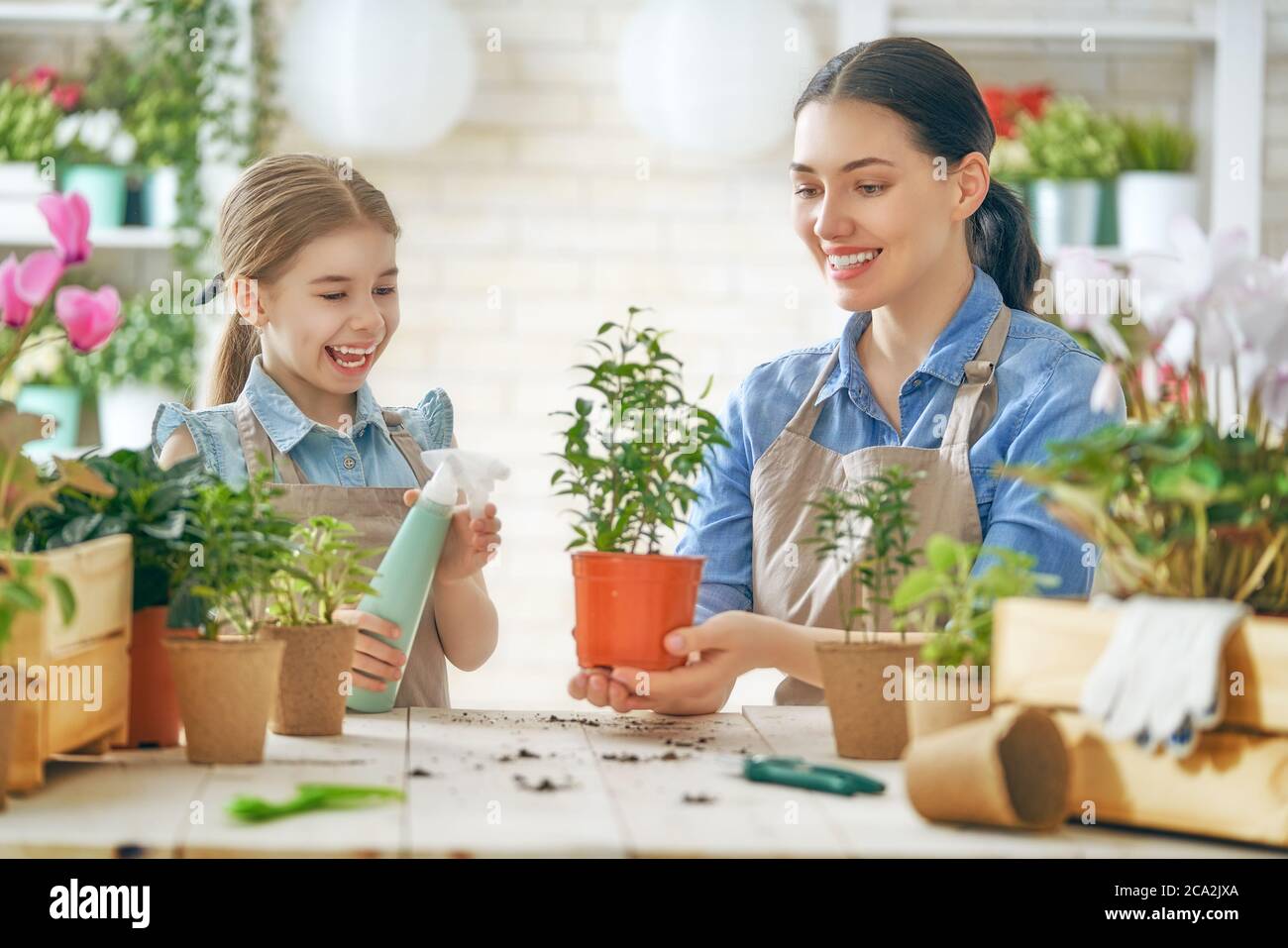 Nettes Kind Mädchen hilft ihrer Mutter für Pflanzen zu kümmern. Mutter