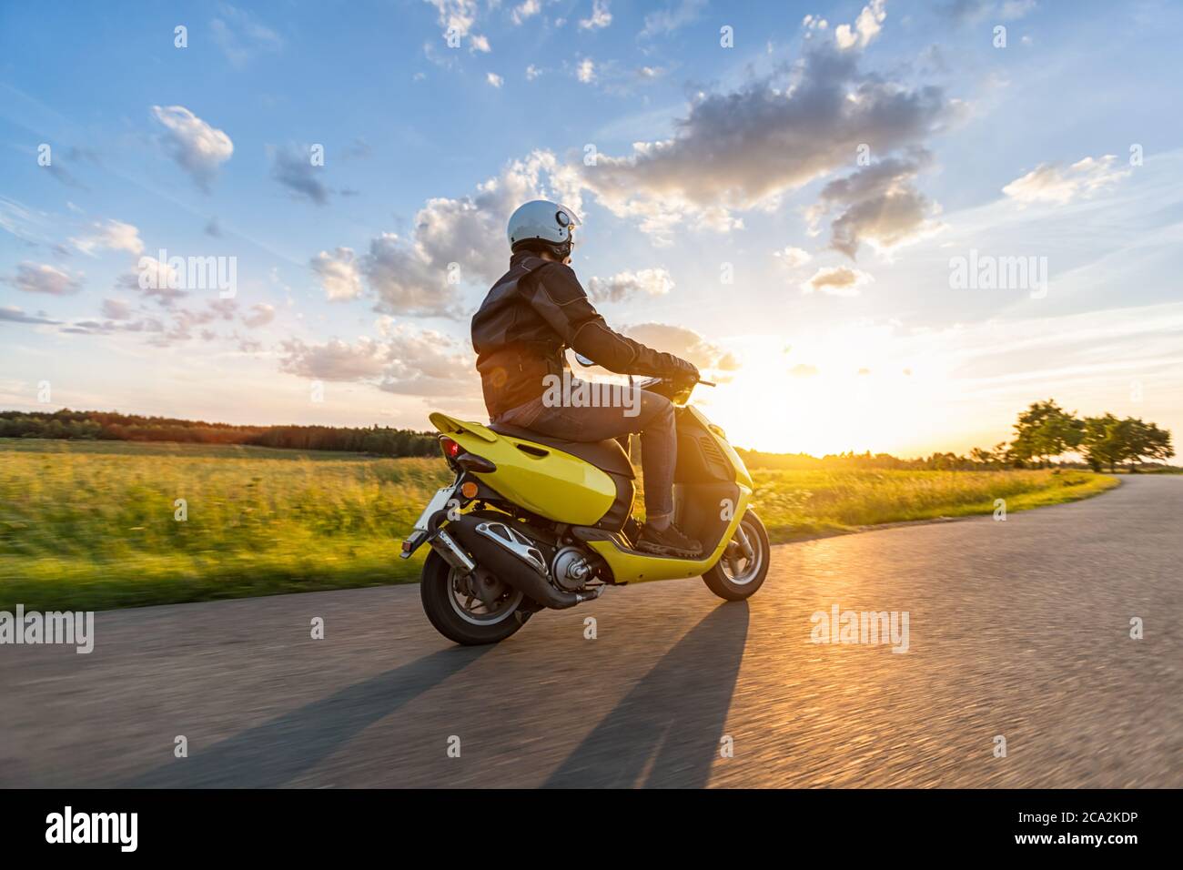 Motorradfahrer fahren auf leerer Straße mit Sonnenuntergang Licht, Konzept von Geschwindigkeit und Touren in der Natur. Kleiner Motorroller Stockfoto