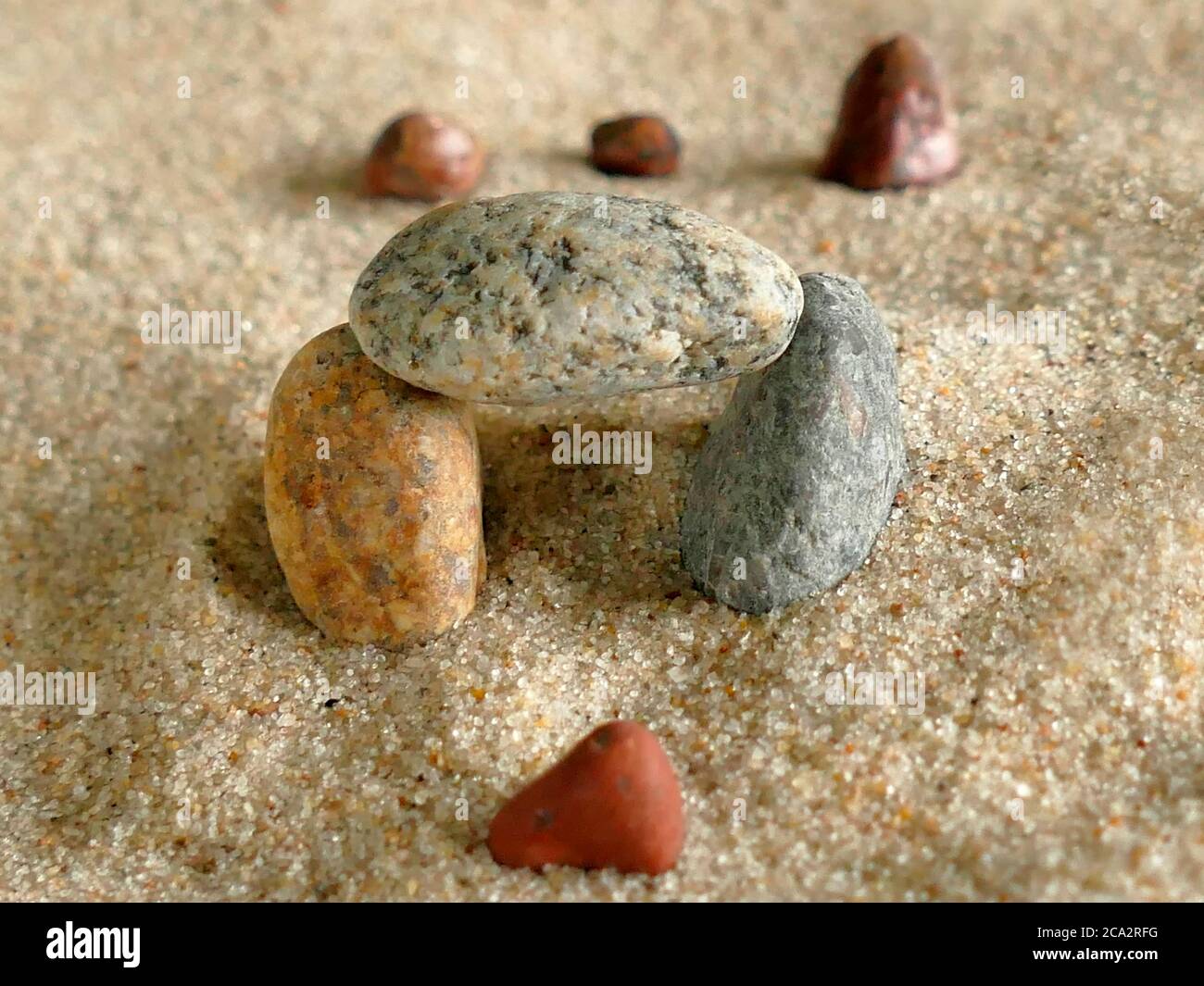 Symbolisches Bild des Durchgehens eines Tores mit Steinen im Sand Stockfoto