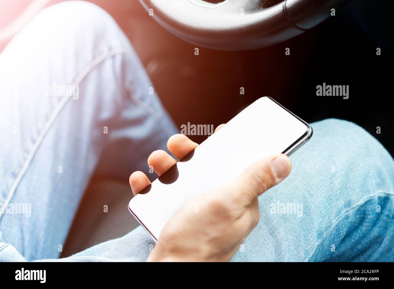 Männliche Hand mit Smartphone im Auto. Mann, der ein Auto fährt. Smartphone im Auto für Navigieren oder GPS. Mobiltelefon in der Hand des Fahrers. Stockfoto