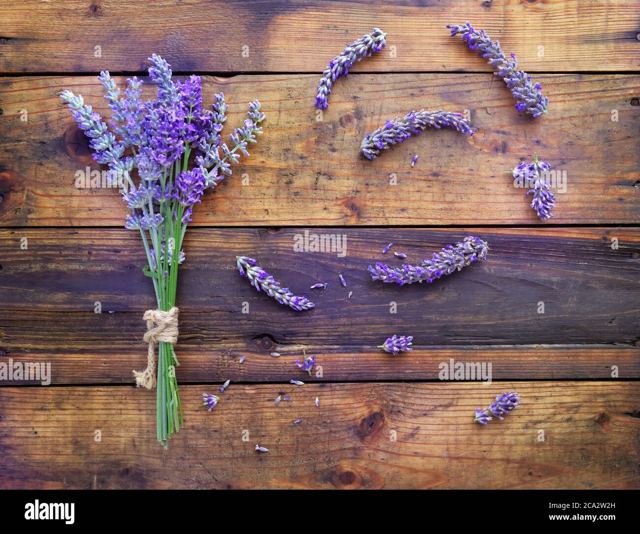 Strauß Lavendelblüten und Blütenblätter auf rustikalem Holzhintergrund Stockfoto