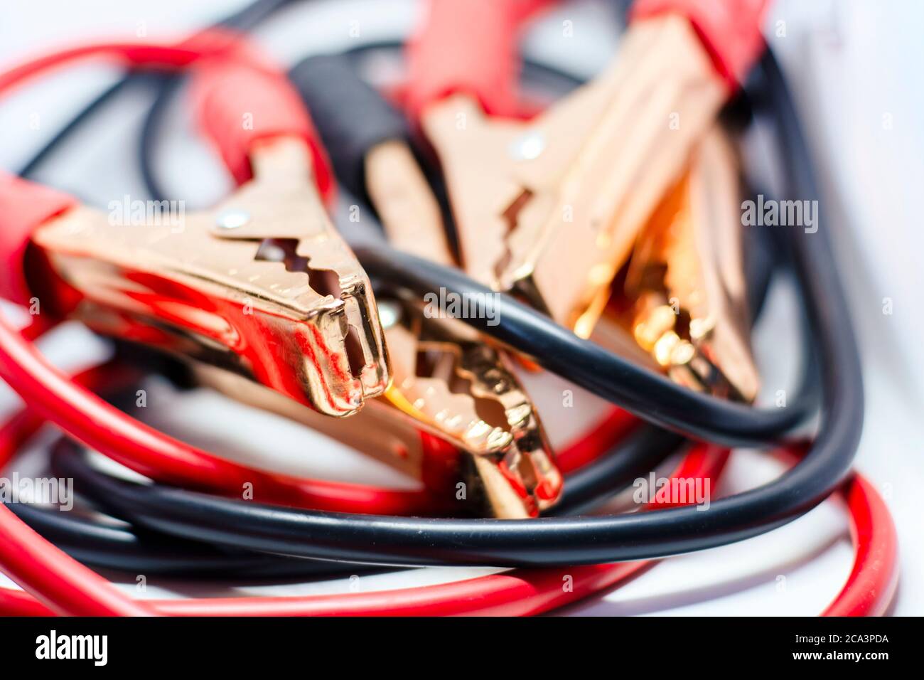 Nahaufnahme des roten und schwarzen Autobatterie-Jumper-Kabels, isoliert auf weißem Hintergrund. Ladekabel. Konzentrieren Sie sich auf Metall Stockfoto