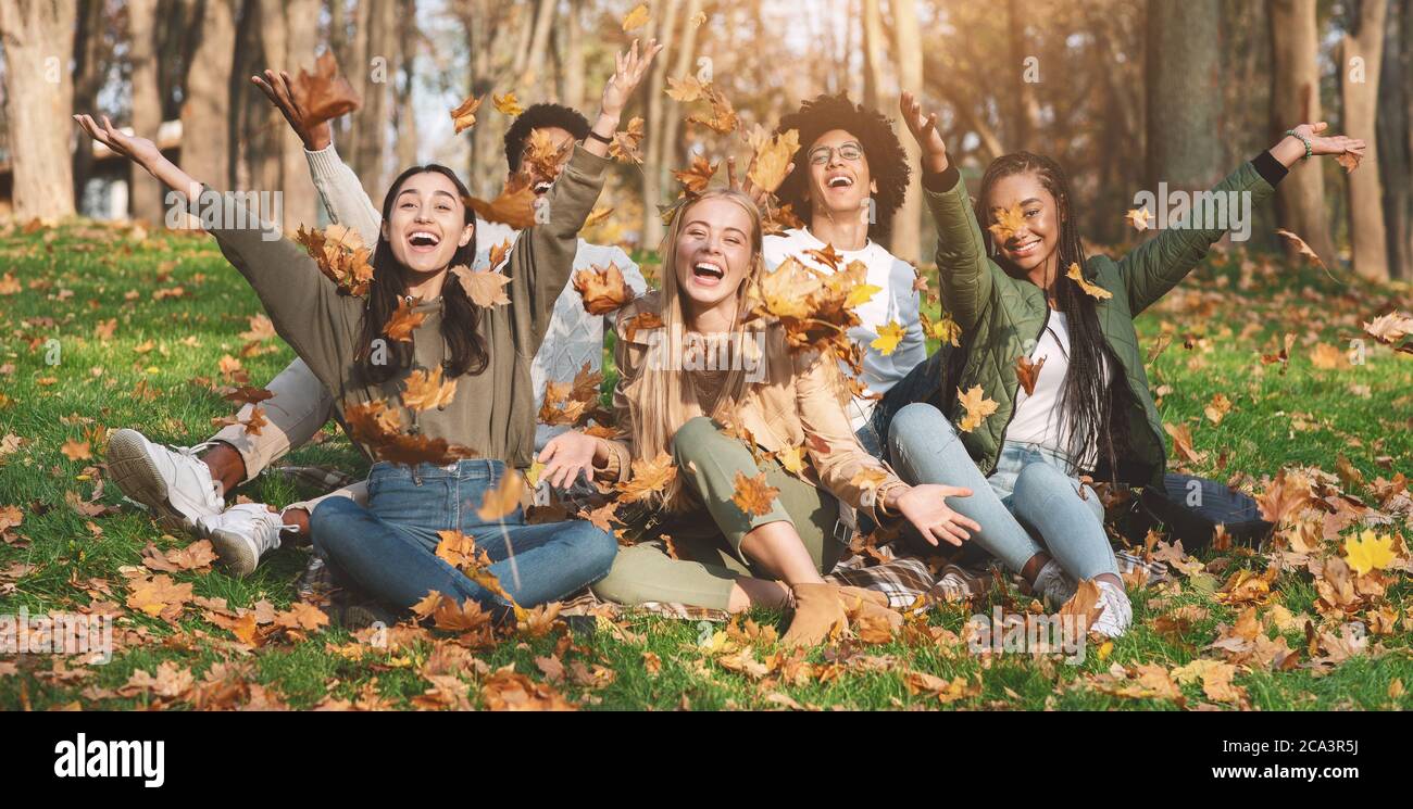 Unbeschwerte junge Freunde fotografieren mit Herbstblättern im Park Stockfoto