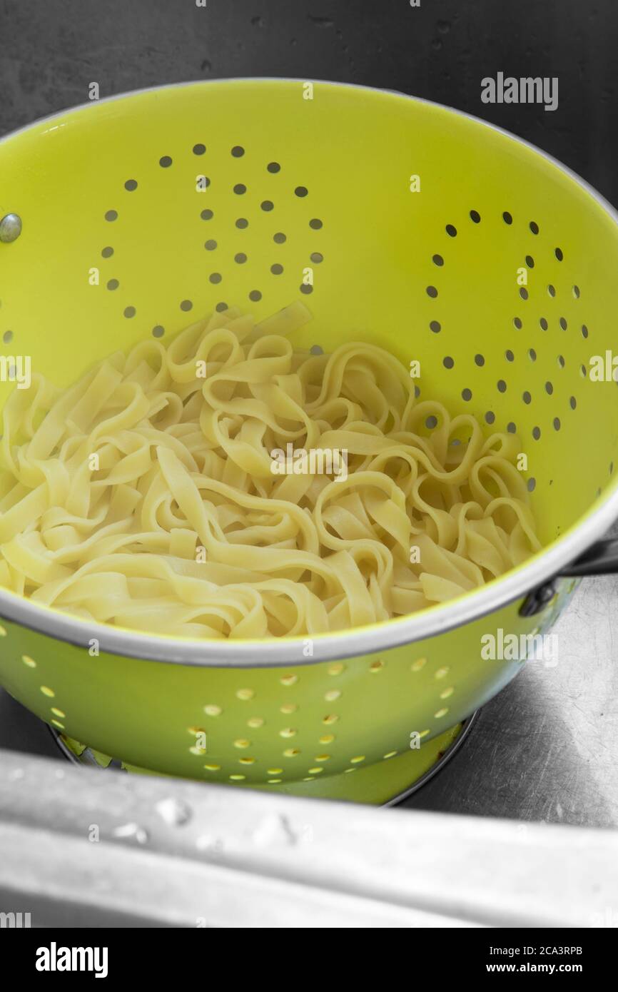 Gekochte Tagliatelle Pasta in einem Sieb in einem Metallwaschbecken Stockfoto