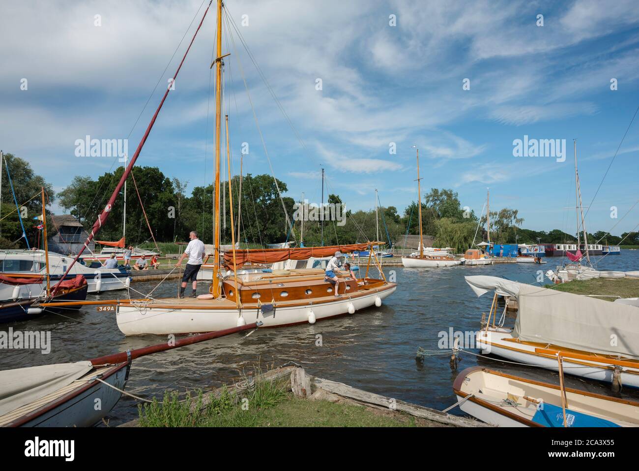 Familiensegeln, Blick im Sommer auf eine Familiengruppe, die ihr Boot entlang einer Wasserstraße in den Norfolk Broads, England, Großbritannien, navigiert Stockfoto
