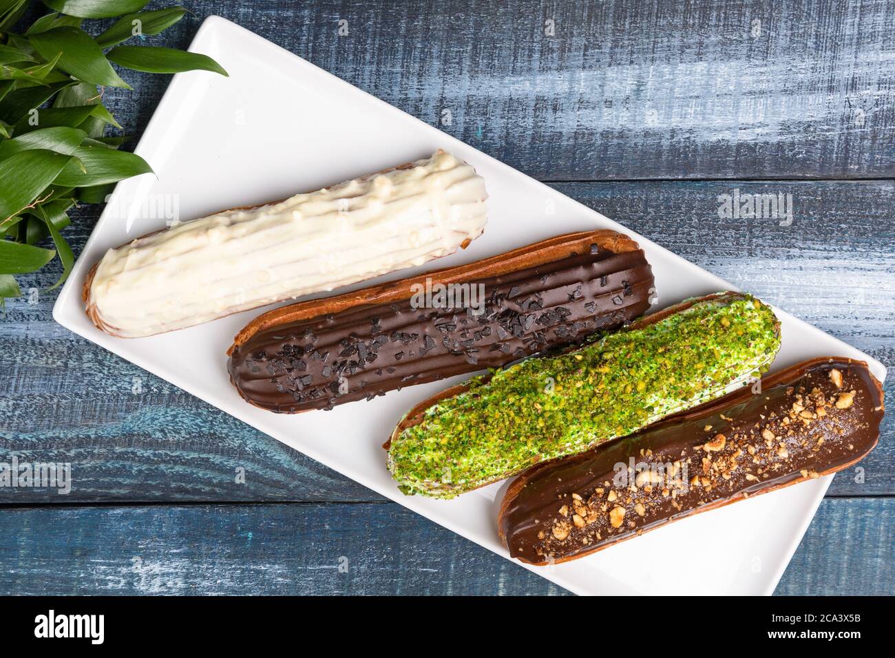 Leckere Schokolade eclair Kuchen mit Blättern auf dem blauen Hintergrund, Draufsicht Stockfoto