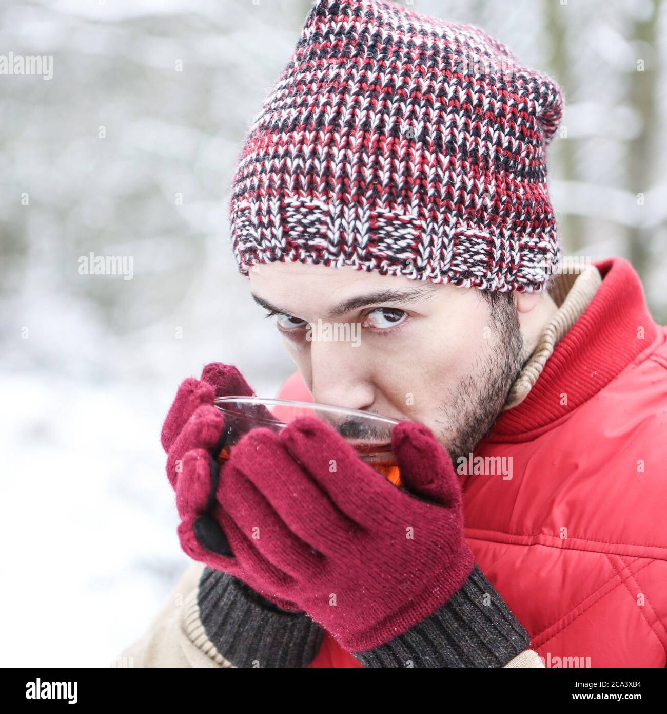 Mann im Winter im Schnee trinkt eine heiße Tasse Tee Stockfoto