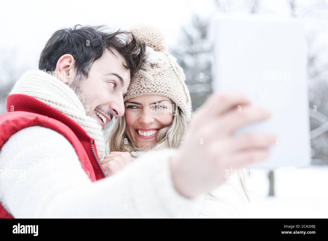 Laughing Couple macht im Winter Selbstporträts mit Tablet-Computer Stockfoto