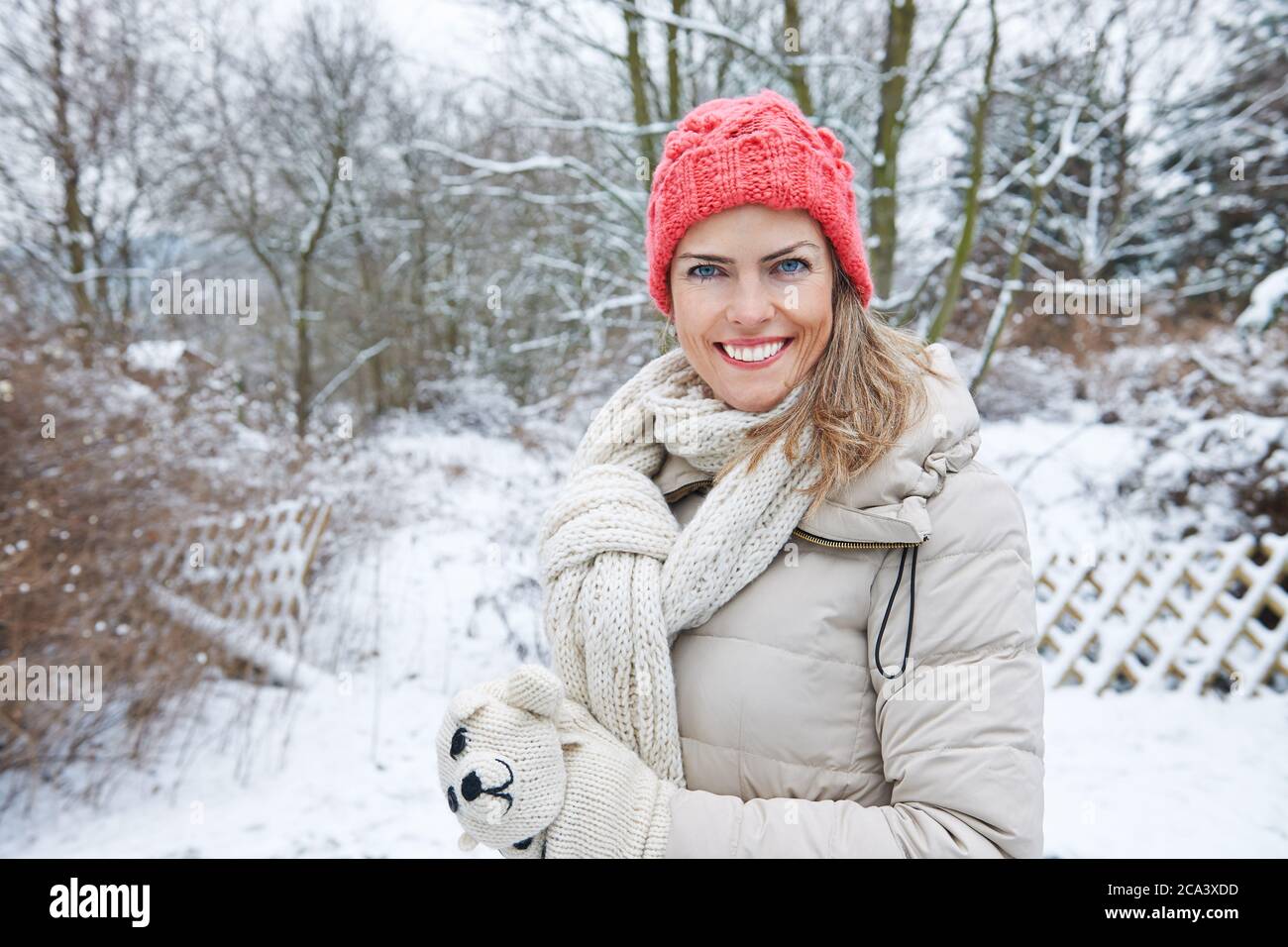 Glückliche Frau im Winter steht im verschneiten Garten Stockfoto