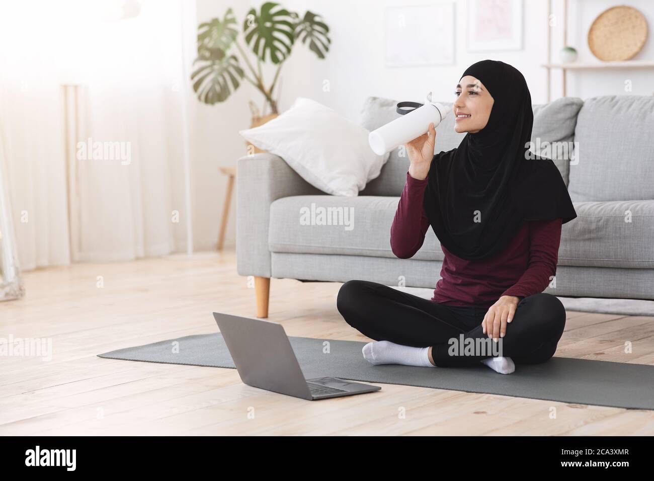 Glückliche Arabische Frau Trinkwasser, Pause Während Fitness-Workout Zu Hause Stockfoto