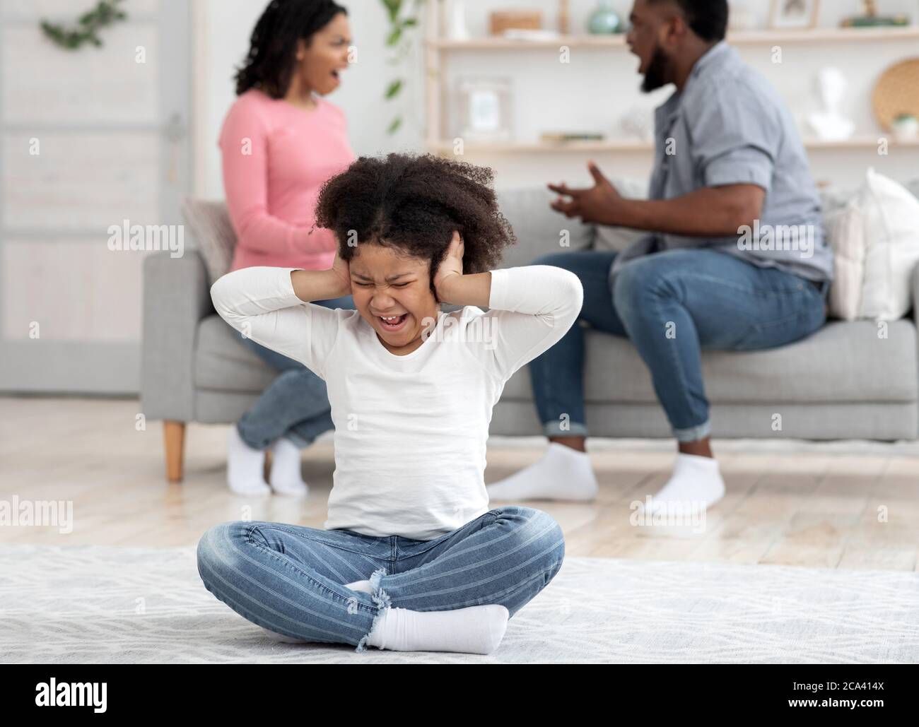 Traumata Im Kindesalter. Kleines Schwarzes Mädchen, Das Ohren Bedeckt, Um Die Eltern Nicht Zu Hören Stockfoto