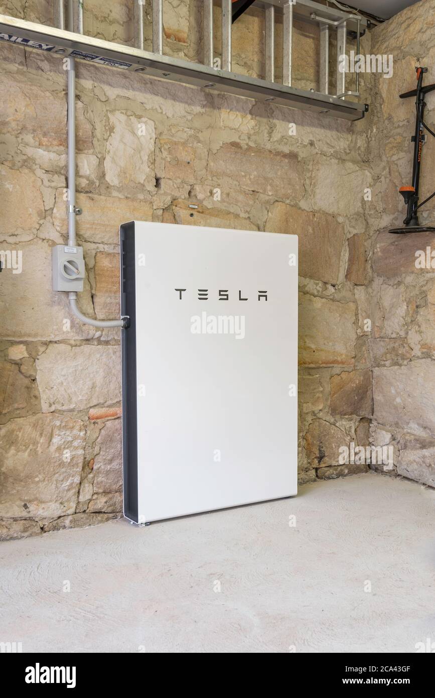 In einer Garage eines Hauses aus den 1920er Jahren mit handgeschnittenen Sandsteinwänden sitzt eine brandneue Tesla Powerwall 2, solarbetriebene Batterie in Sydney, Australien Stockfoto