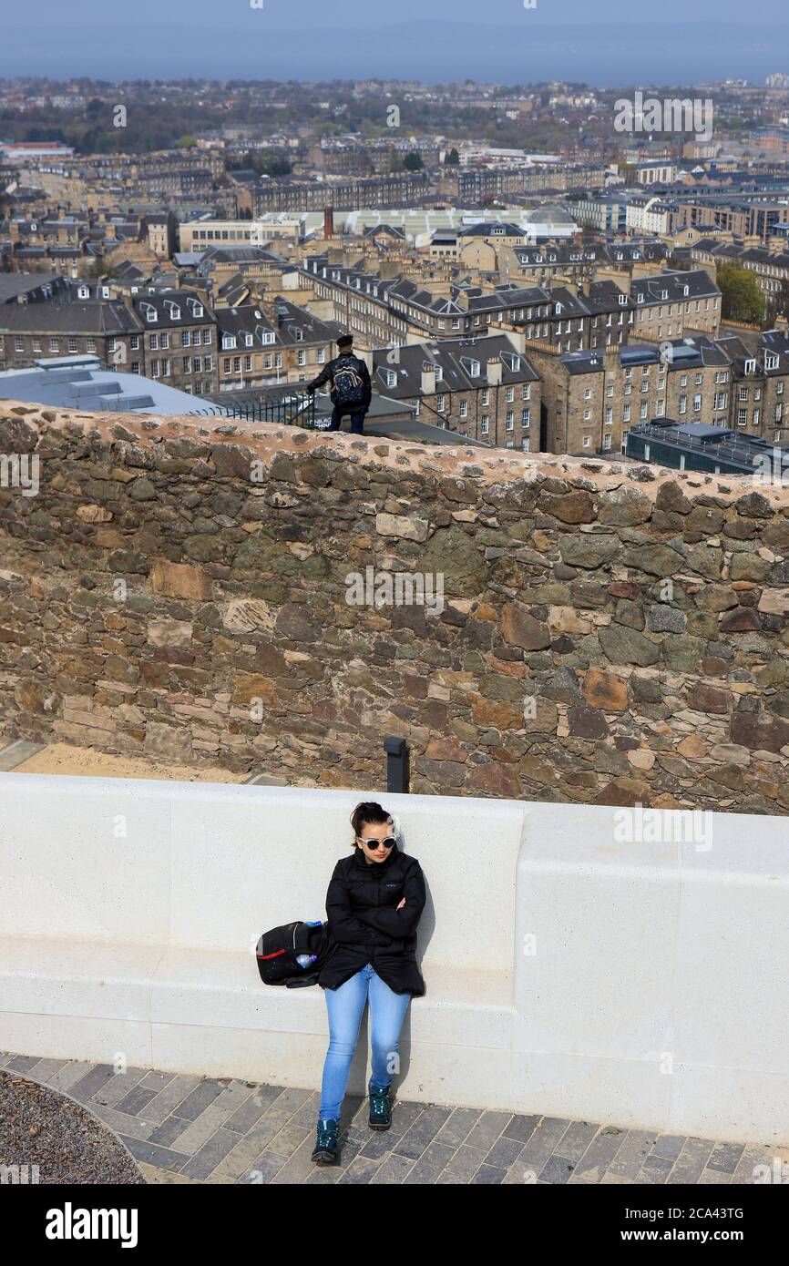 Frau, die vom Calton Hill aus den Blick auf die Altstadt von Edinburgh mit einem Mann über die Grenzmauer des Observatoriums in Richtung Leith nimmt Stockfoto