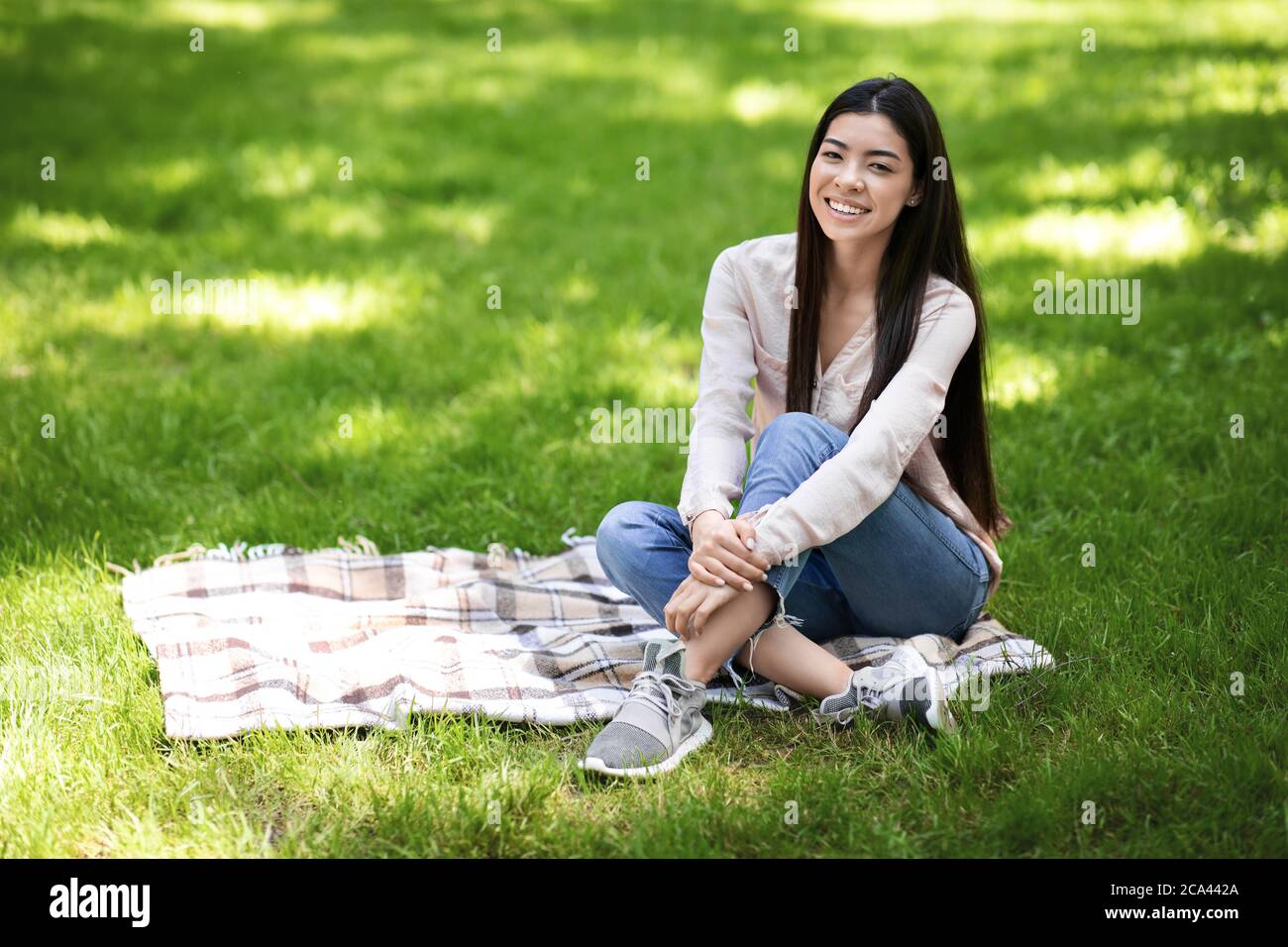 Entspannen Sie Sich Im Freien. Portrait Von Young Asian Girl Sitzend Auf Plaid Im Park Stockfoto