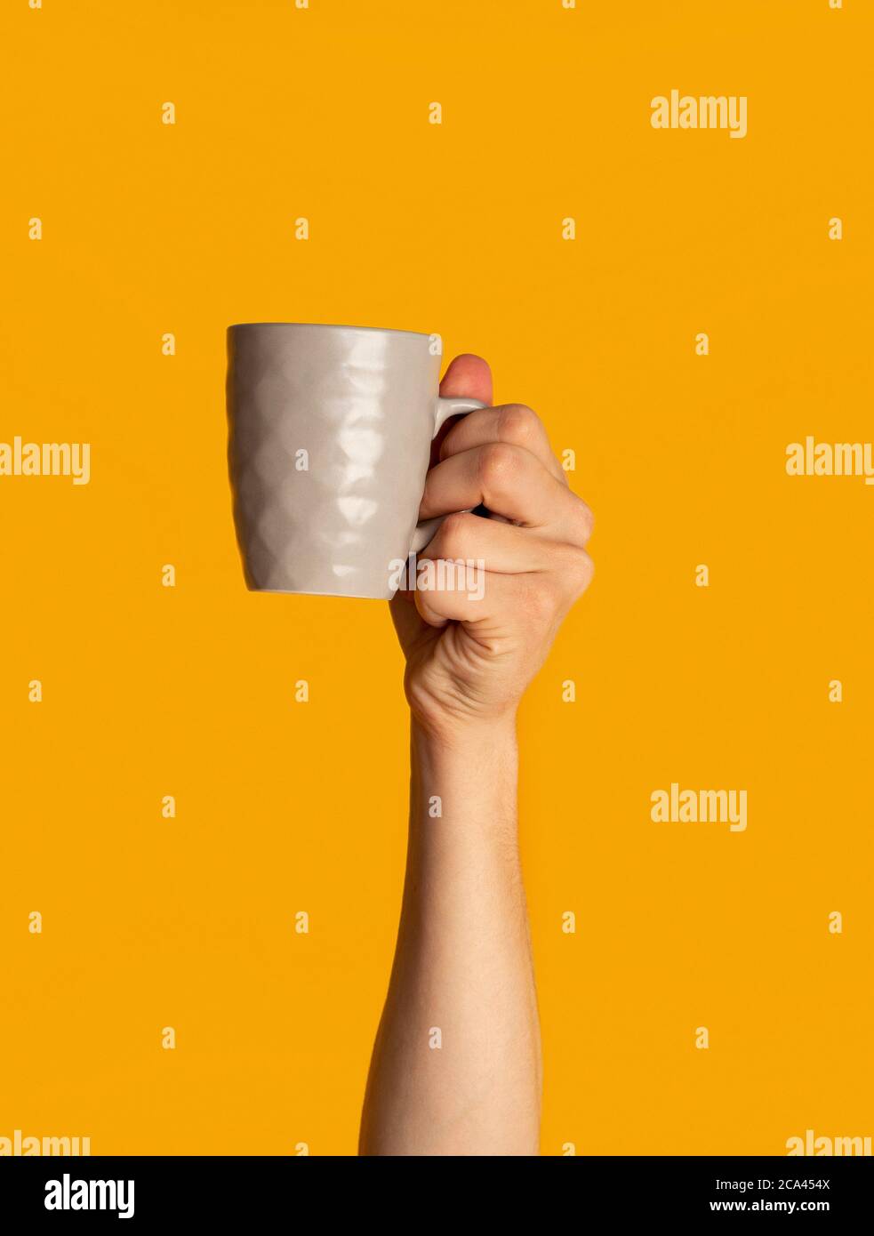 Millennial Kerl zeigt Tasse heißes Getränk auf orangenen Hintergrund, Nahaufnahme Stockfoto