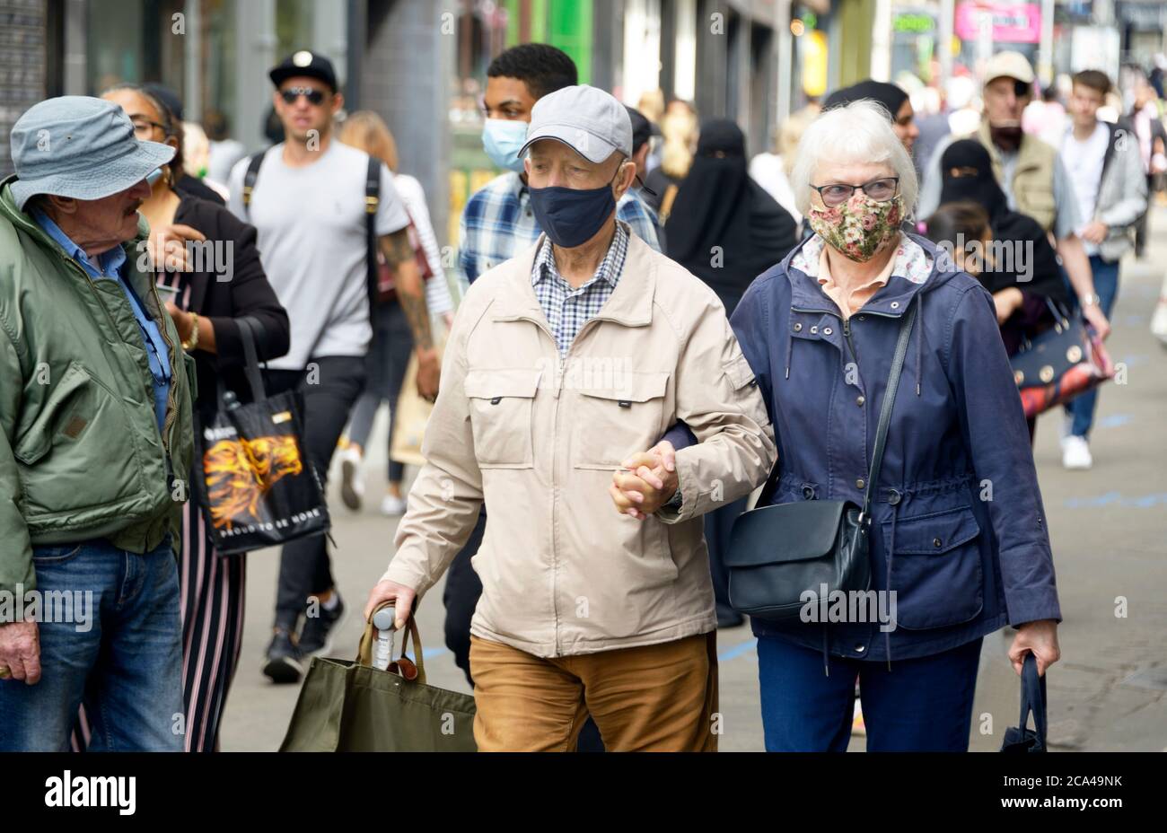 Ältere Paare, die zusammen gehen, Hände halten und Masken tragen, während COVID 19 nach dem Lockdown. Stockfoto