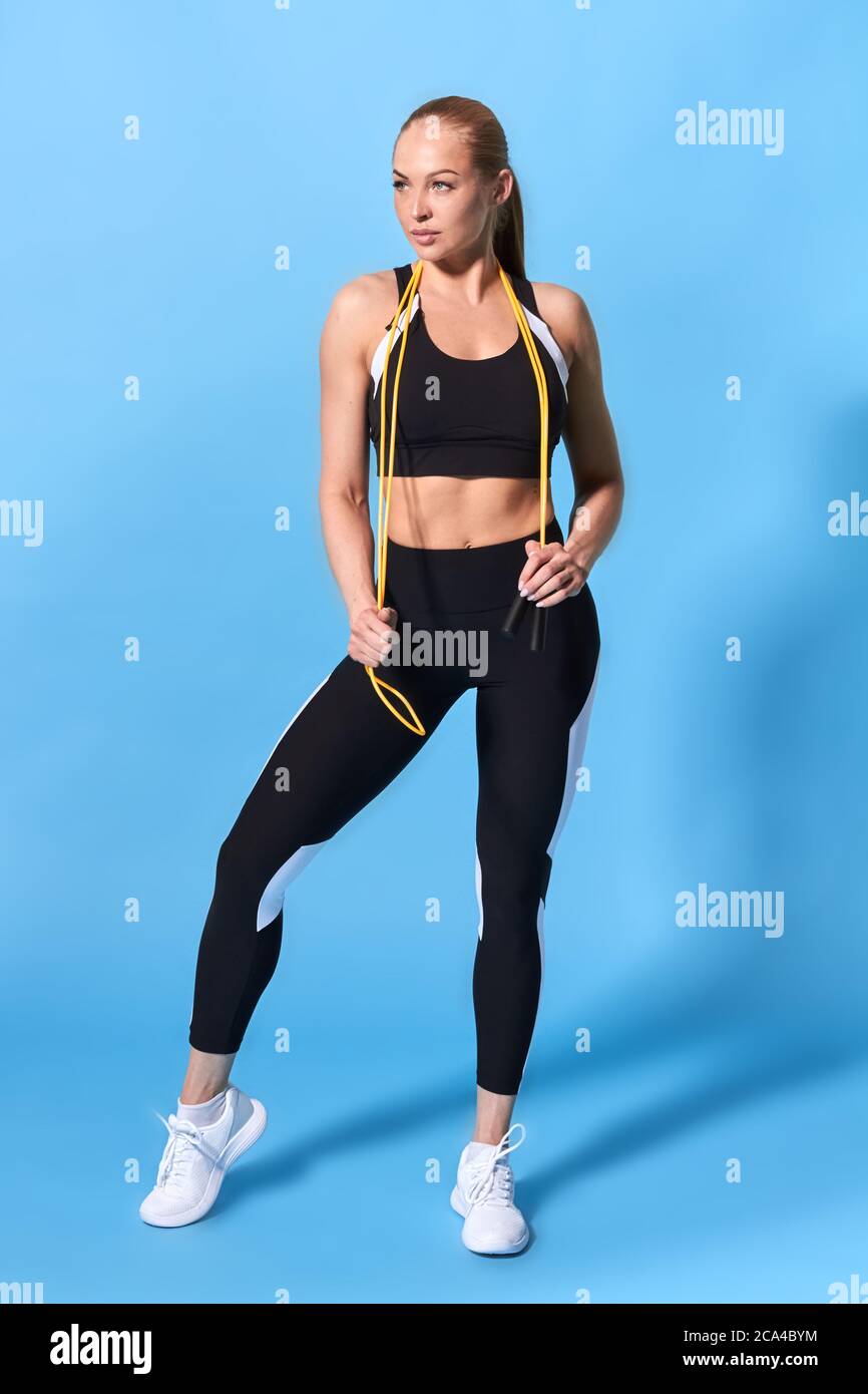 Schöne attraktive Sportlerin mit Überspringen Rop auf ihren Schultern suchen Seite, in voller Länge Foto. Isolierte blauen Hintergrund Stockfoto