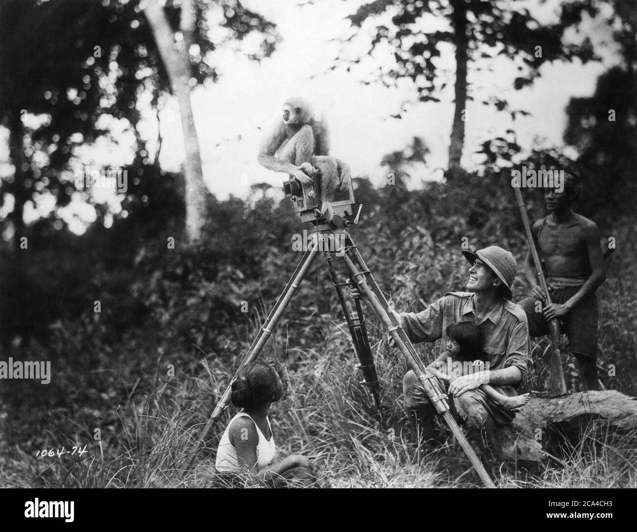 Regisseur ERNEST B. SCHOEDSACK am Drehort offen mit Einheimischen und BIMBO dem Affen in Nord-Siam (jetzt Thailand) während der Dreharbeiten zum Dokumentarfilm CHANG : A Drama of the Wilderness 1927 Regisseure / Produzenten MERIAN C. COOPER und ERNEST B. SCHOEDSACK Famous Players - Lasky Corporation / Paramount Pictures Stockfoto