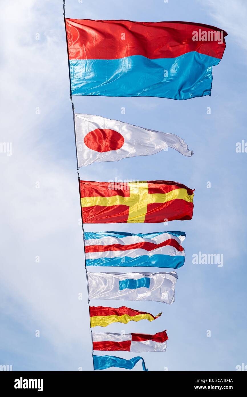 Nautische Flaggen gegen blauen Himmel im Wind an sonnigen Tag, vertikal. Stockfoto