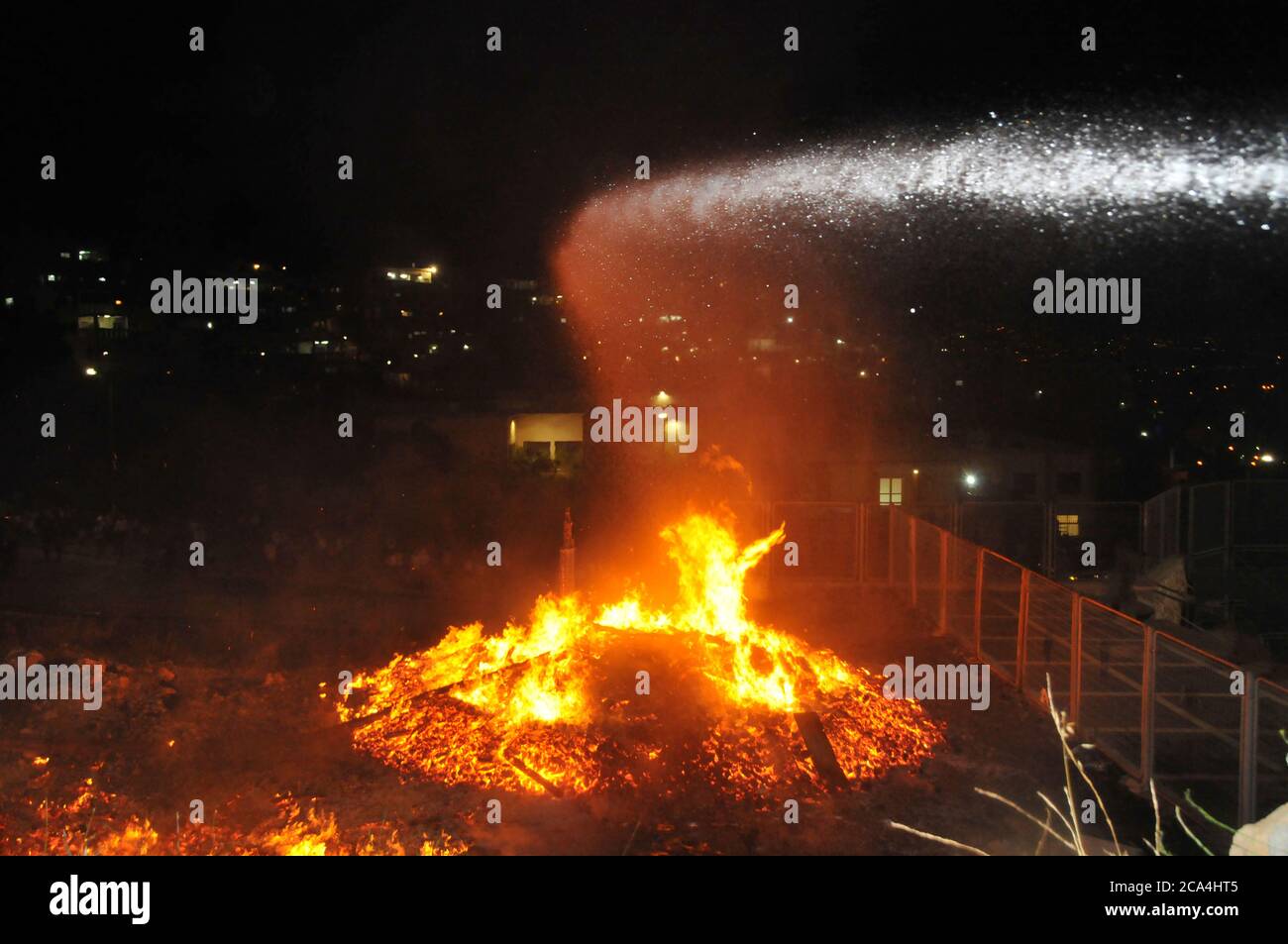 Feuerwehrmann ein großes Lagerfeuer, während die Lag B'Omer feiern (Lag B'Omer ist ein Tag für Lagerfeuer feiern löschen.) Stockfoto