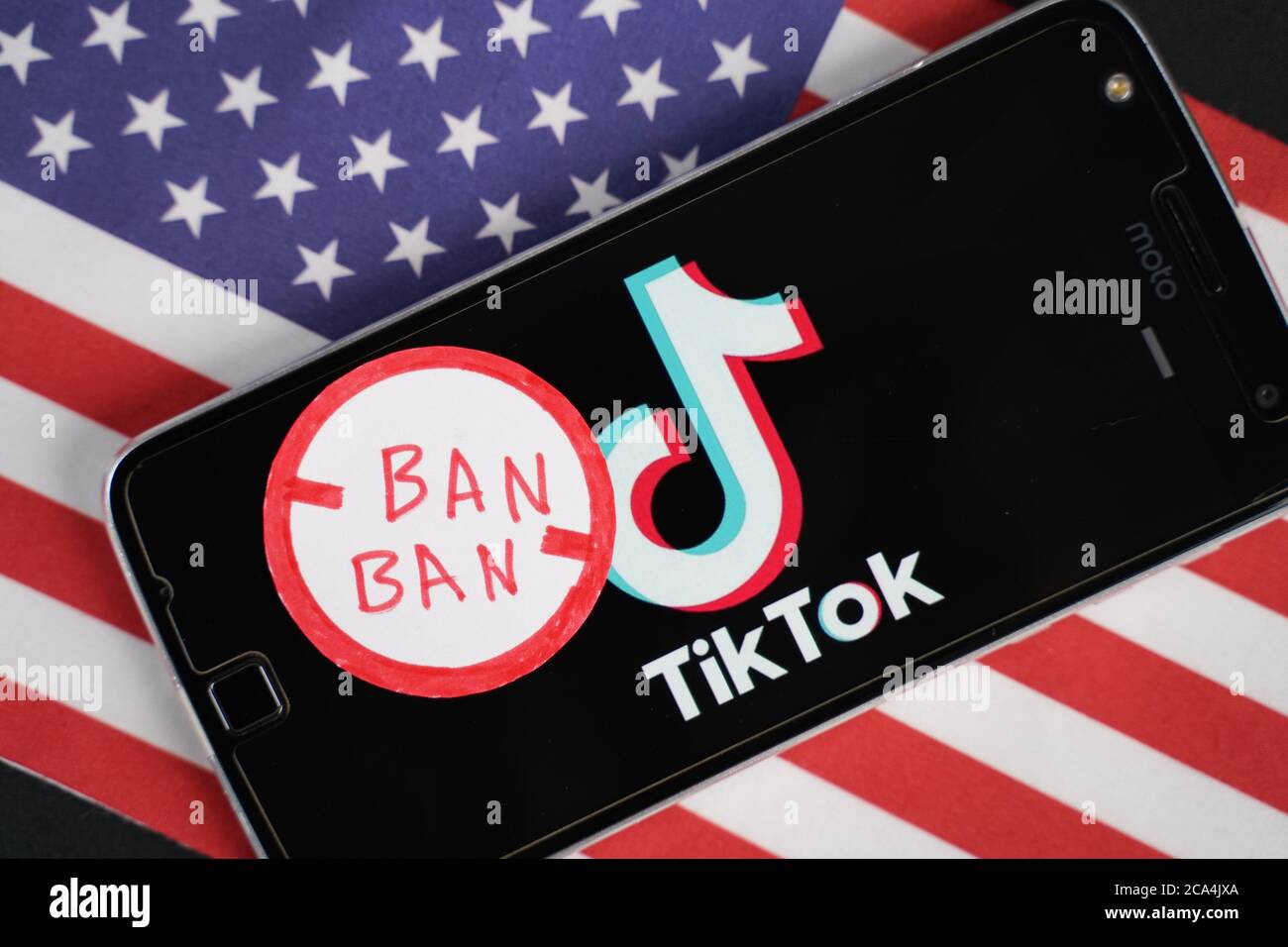 Maski, Indien - 4. August, 2020 : TikTok Logo auf Telefon und Verbotsstempel mit Amerika Flagge Hintergrund. Stockfoto