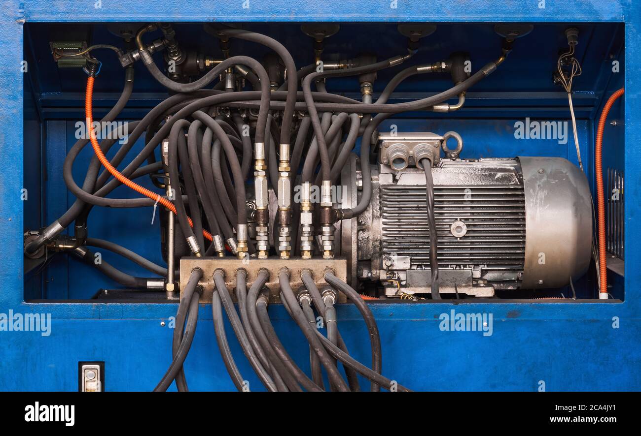 Industrieller Hintergrund - Elektromotor, Pumpe und Regelventile mit Schläuchen einer hydraulischen Maschine aus der Nähe Stockfoto