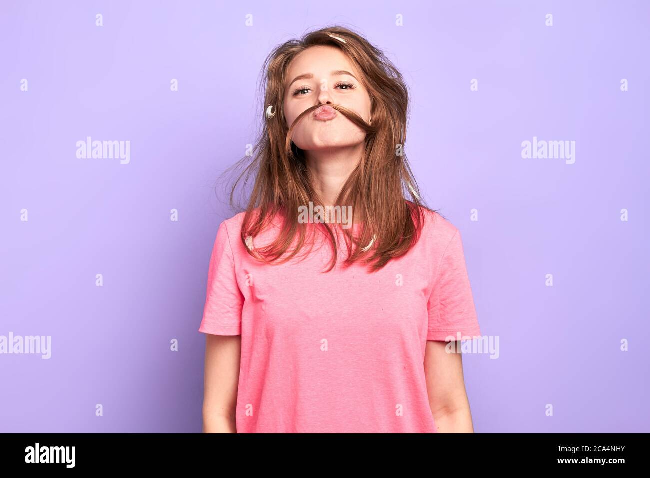 Portrait Aufnahme von fröhlichen lustigen Mädchen mit verspielten Stimmung, Schnurrbart mit ihren Haaren, Scherz und mit viel Spaß mit Freunden bei Pyjamas Party, Stockfoto