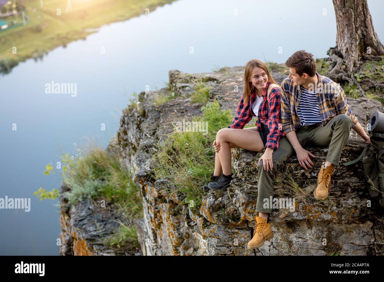 Junges Paar sitzt auf einem Felsen mit einem Gespräch, reden, wunderbare nture im Hintergrund des Fotos. Freundschaft. Menschen, Lebensstil, Spare t Stockfoto