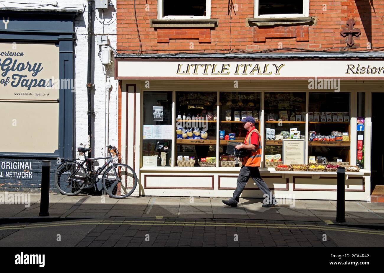 Postbote, der an Little Italy Café, Goodramgate, York, North Yorkshire, England vorbeiläuft Stockfoto