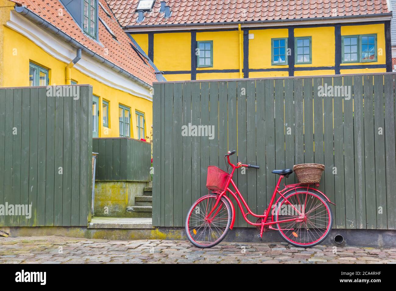 Rotes Fahrrad gegen einen grünen Zaun in der Altstadt von Ribe, Dänemark Stockfoto