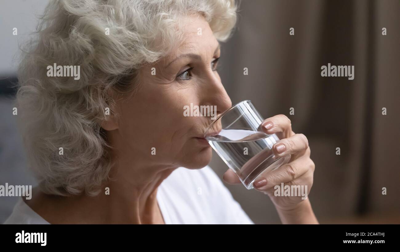 Ältere Frau hält Glas still trinken oder Mineralwasser Stockfoto