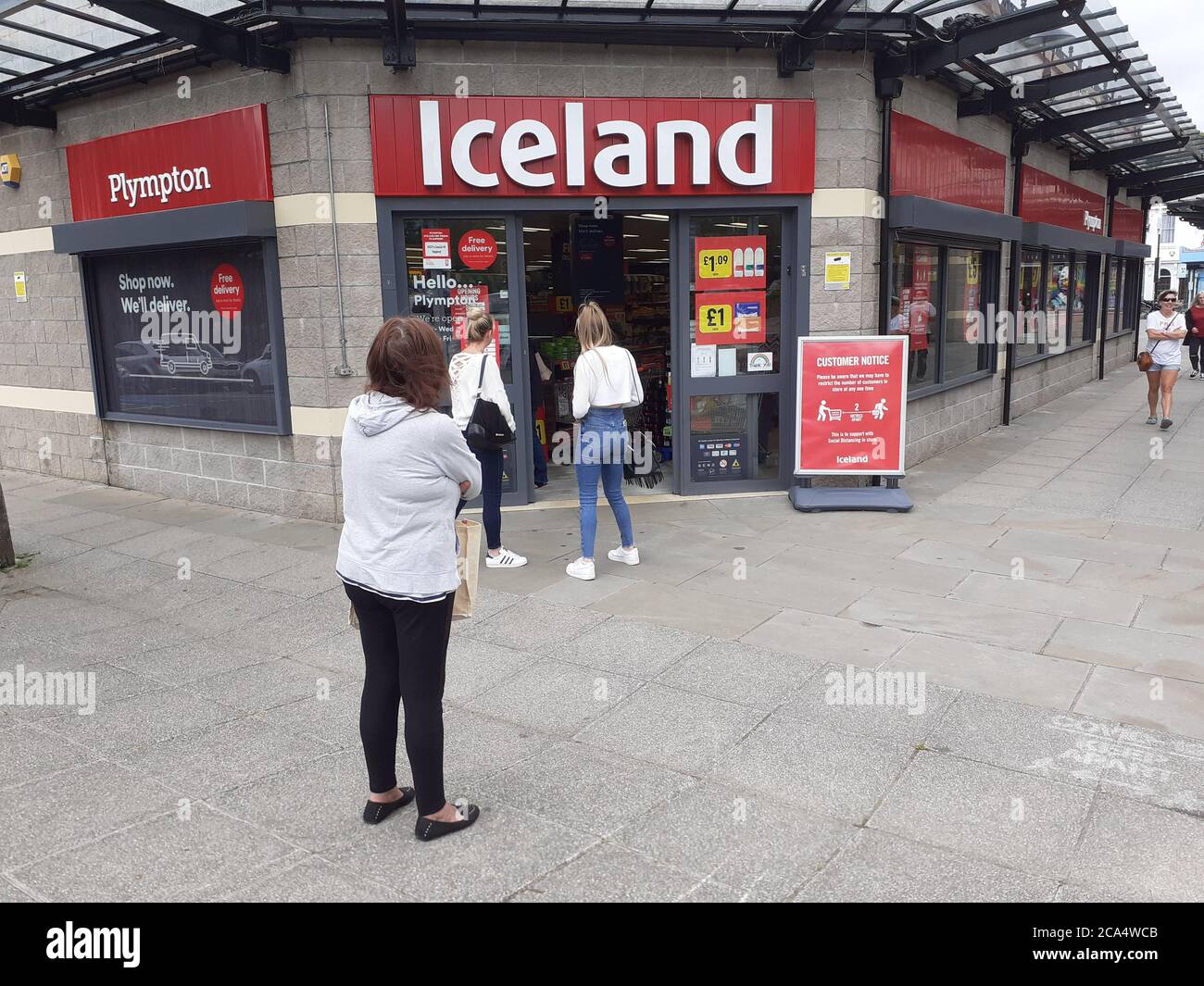 Schlange von Menschen außerhalb zeigen auf Höhe der Beschränkungen warten Zum Kauf von Waren und Einkaufen Covid 19 Coronavirus Soziale Distanzierung Stockfoto