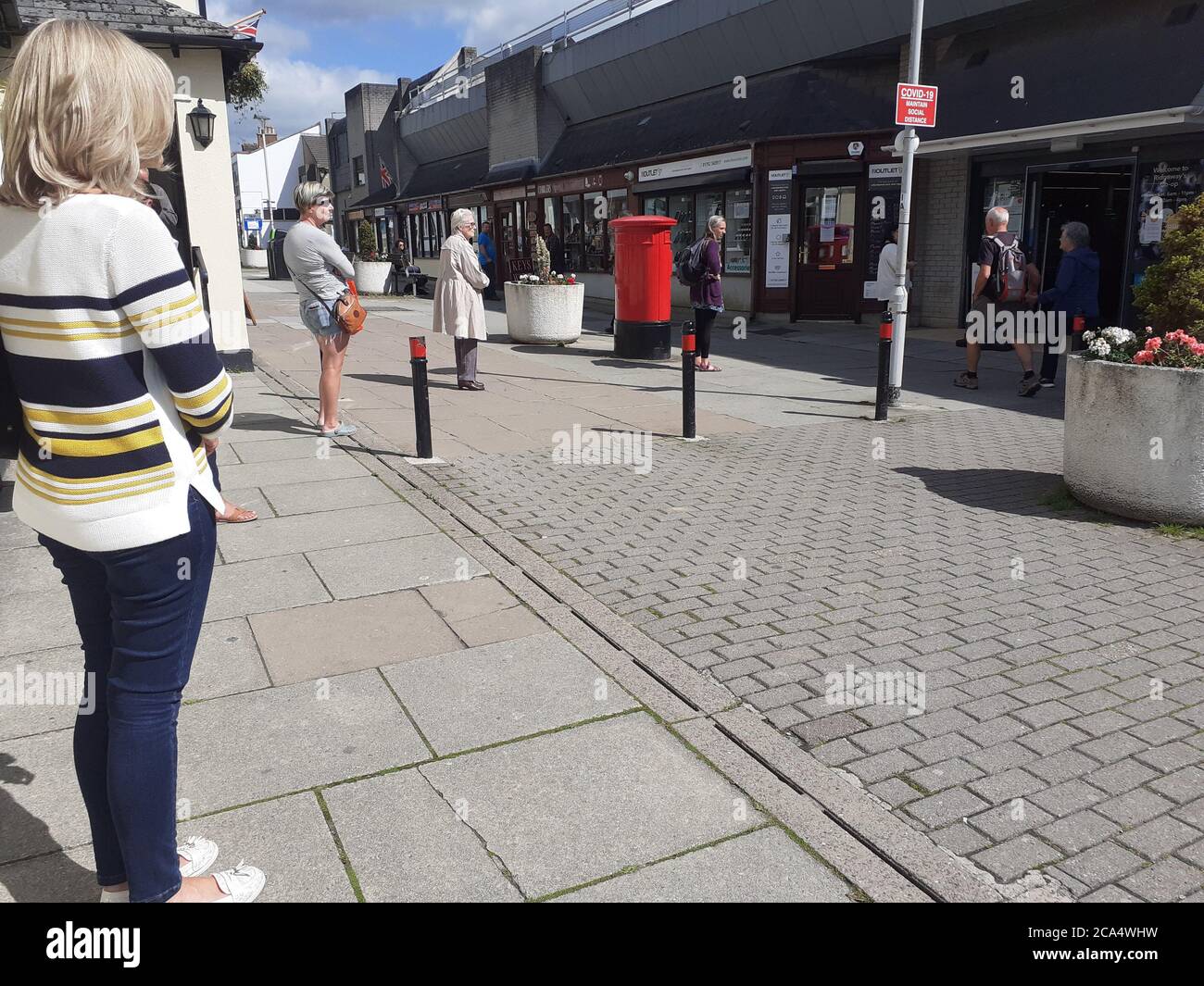 Schlange von Menschen außerhalb zeigen auf Höhe der Beschränkungen warten Zum Kauf von Waren und Einkaufen Covid 19 Coronavirus Soziale Distanzierung Stockfoto