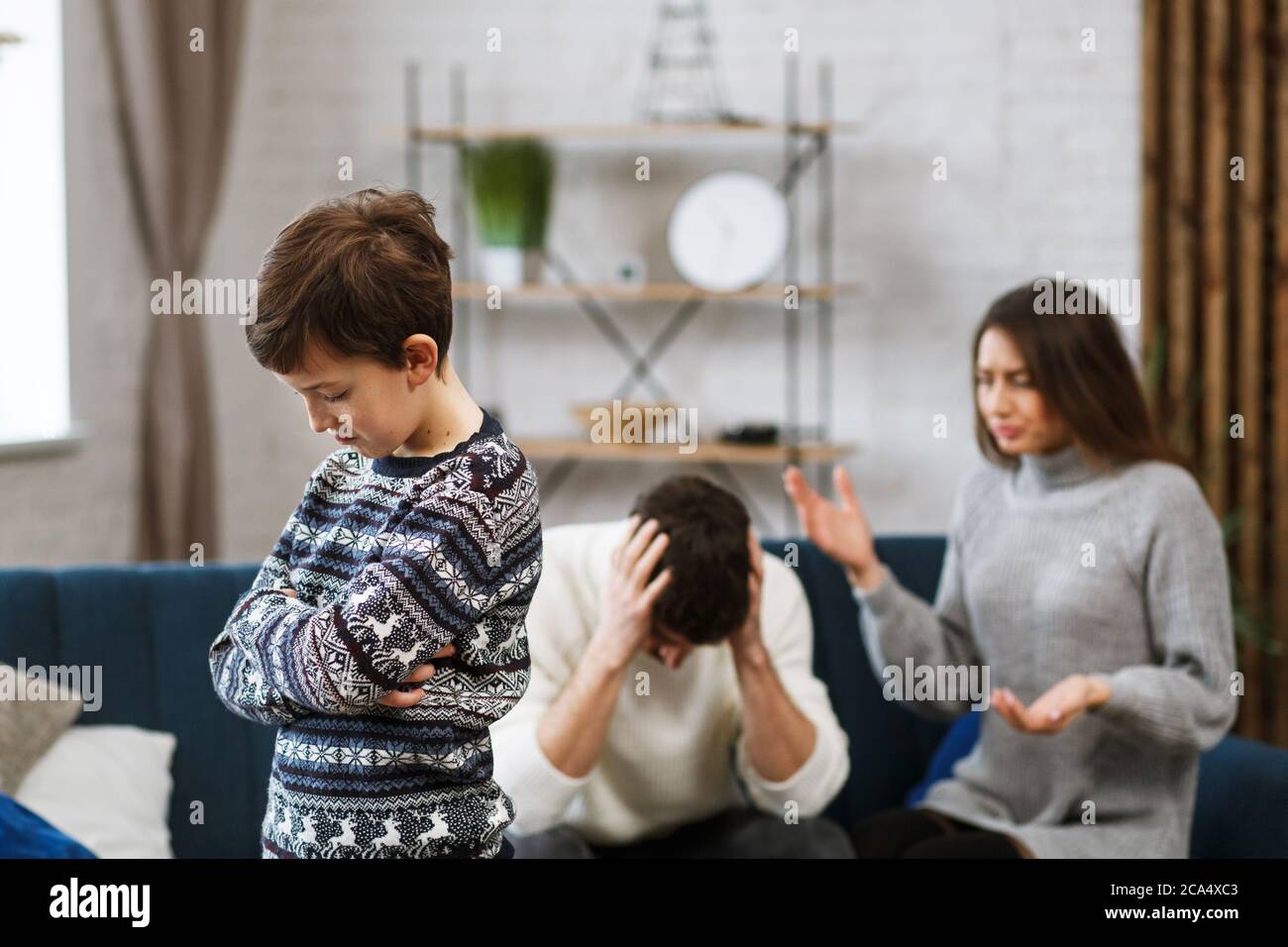 Trauriger kleiner Junge fühlt sich aufgeregt, während seine Eltern im Hintergrund kämpfen. Mutter und Vater streiten. Familienkonflikte und Scheidung führen zu Kindern Stockfoto