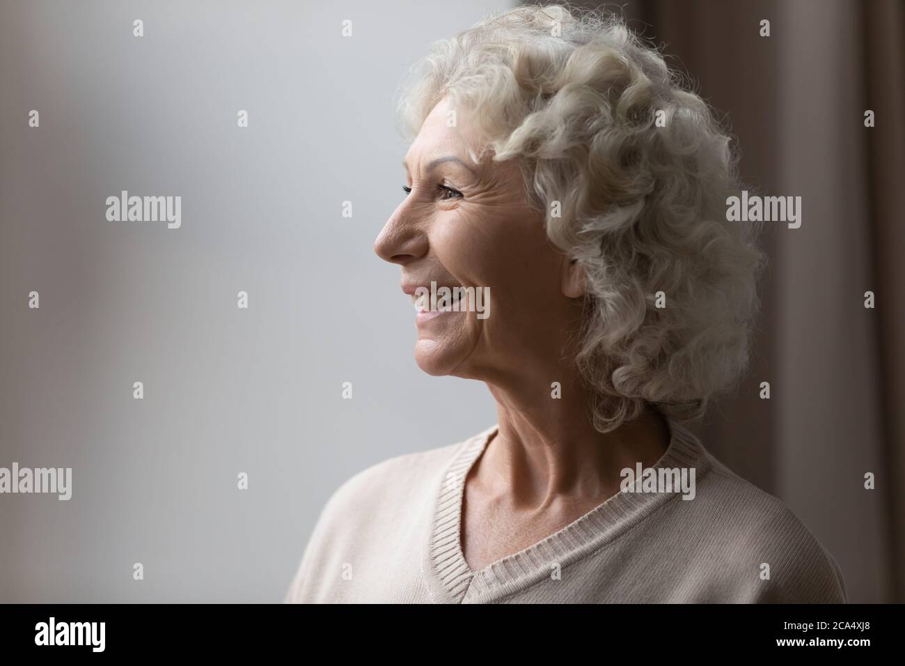 Reife Frau lächelt bewundert Blick vom Fenster fühlt sich sorglos Stockfoto